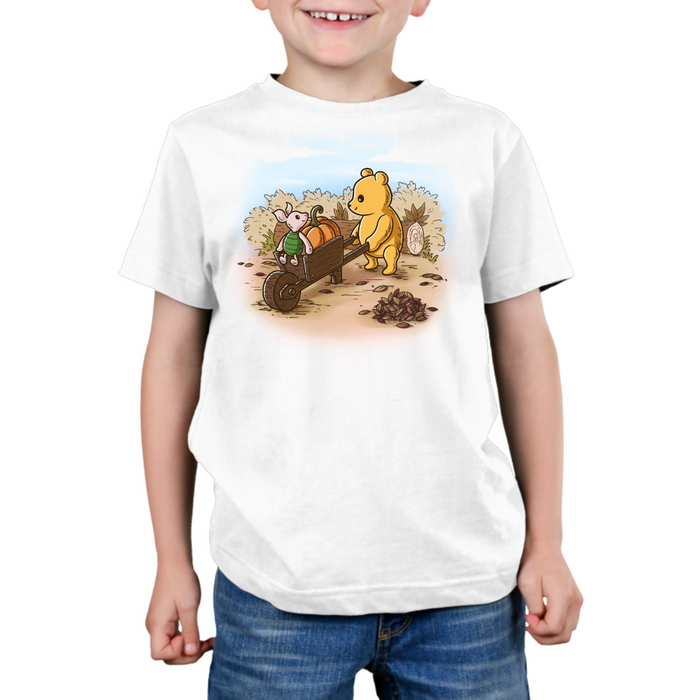 Premium Cotton T-shirt_TeeTurtle white A Perfect Autumn Day Premium Cotton T-shirt featuring a bear pulling a wagon filled with pumpkins while a little mouse rides along, surrounded by autumn bushes, fallen leaves, and tree stumps on a crisp fall day.