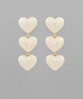 Cream acrylic heart drop earrings featuring three glossy hearts in a cascading design on a neutral background from The Pink Doxie Boutique.