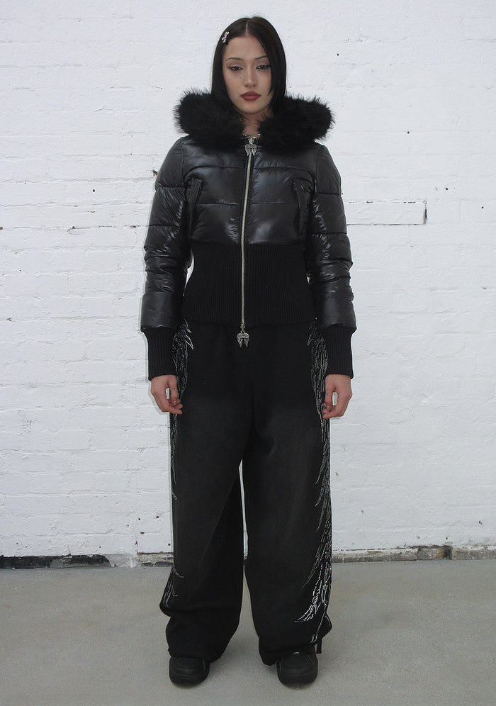 Model wearing the fallen faux fur reversible rib puffer jacket in black with a zip and ribbed details.