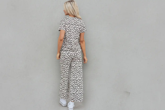 Person wearing a leopard print jumpsuit standing in front of a door with a wreath.