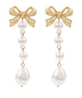 Gold bow drop earrings with linked faux pearl accents on a white background from The Pink Doxie Boutique.